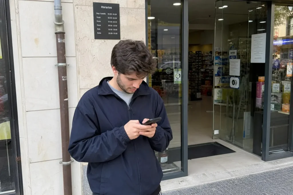 Person utanför butiksentré tittar koncentrerat på sin smartphone, ett vardagsscenario när småföretag digitaliserar småföre...