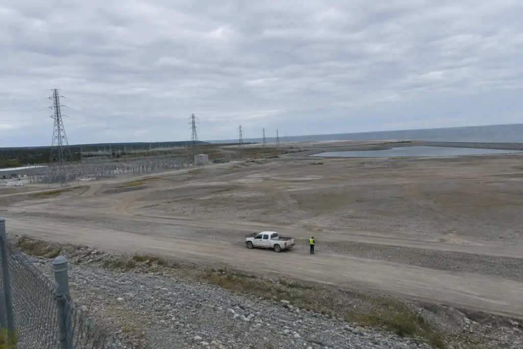 Här planers för storskaligt kärnkraftsprojekt, ett stort öppet kustområde med kraftledningar under en mulen himmel.